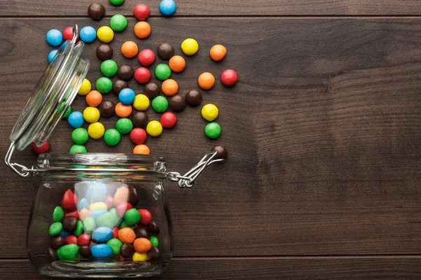 Tarro de vidrio volcado lleno de dulces de colores — Foto de Stock