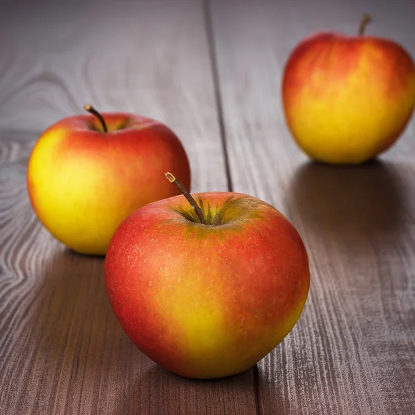 Färska röda äpplen på brun träbord — Stockfoto