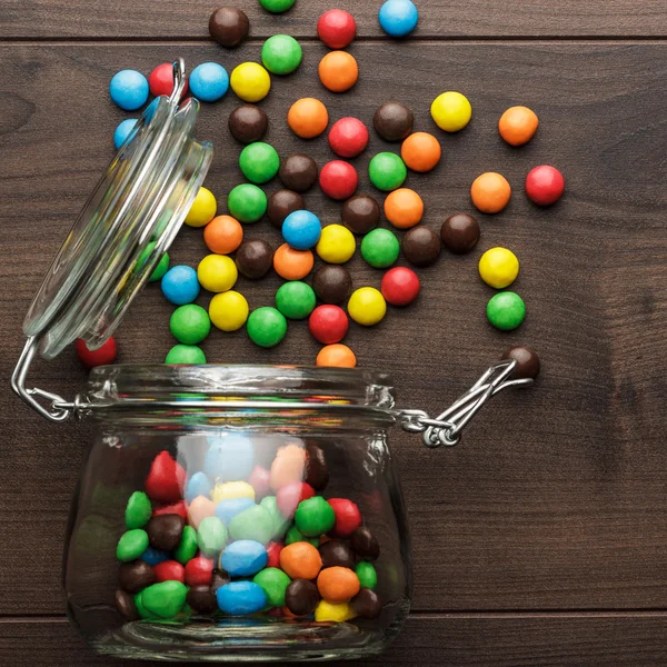 Pot en verre renversé plein de bonbons colorés — Photo