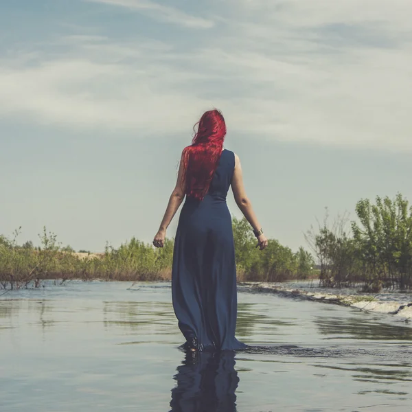 Рыжая женщина, идущая по реке — стоковое фото
