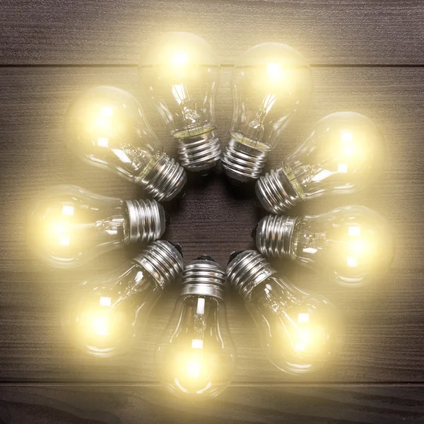 Glowing bulbs on wooden background — Stock Photo, Image