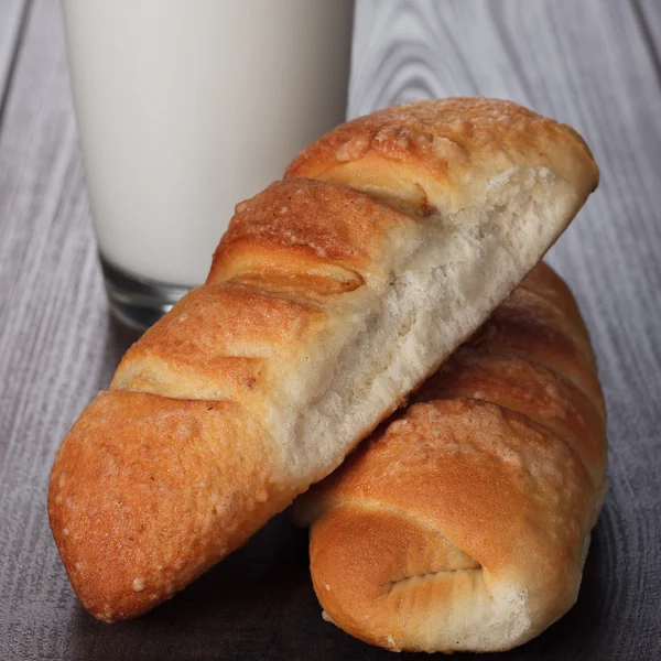 Glas Milch und frische Brötchen auf dem Tisch — Stockfoto