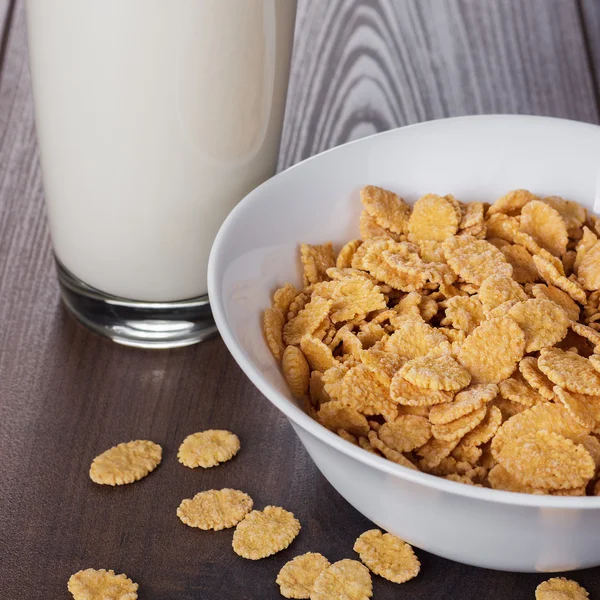 Glass of milk and bowl with cornflakes — Stock Photo, Image