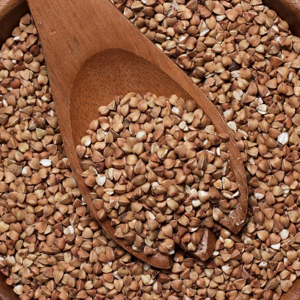 Brown wooden bowl full of buckwheat — Stock Photo, Image