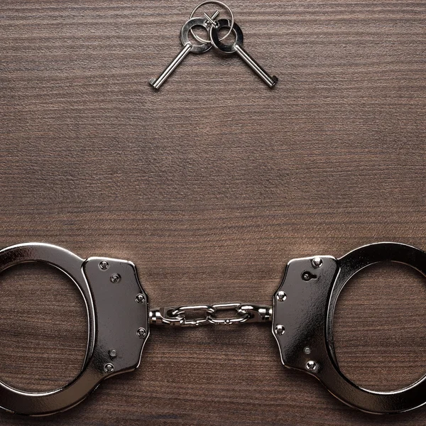 Steel handcuffs and keys on the wooden background — Stock Photo, Image