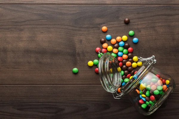 Pot en verre renversé plein de bonbons colorés — Photo