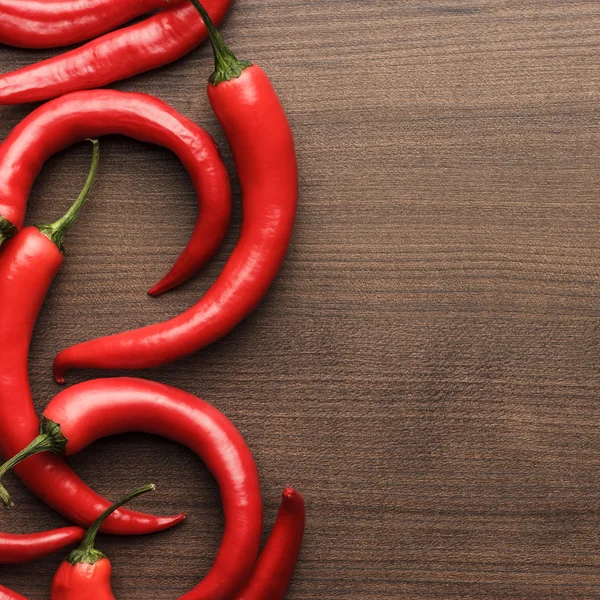 Red hot chilli peppers on wooden table — Stock Photo, Image