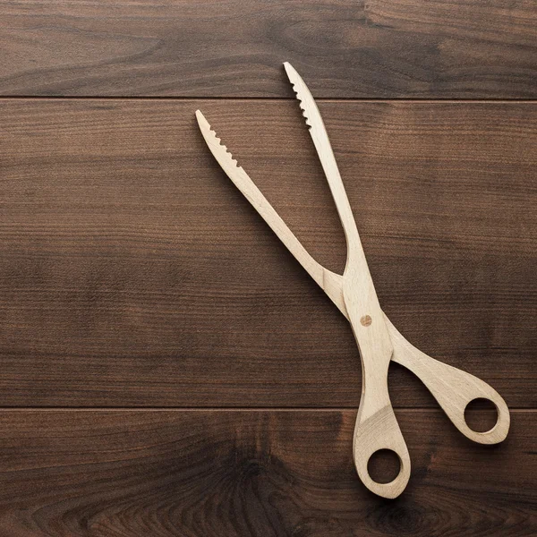 Wooden grill tongs on the table — Stock Photo, Image