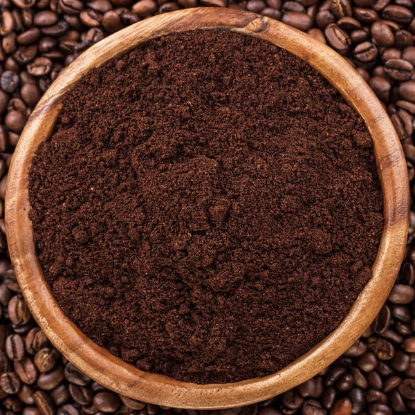 Coffee beans and wooden bowl full of ground coffee — Stock Photo, Image