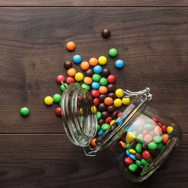 Pot en verre renversé plein de bonbons colorés — Photo