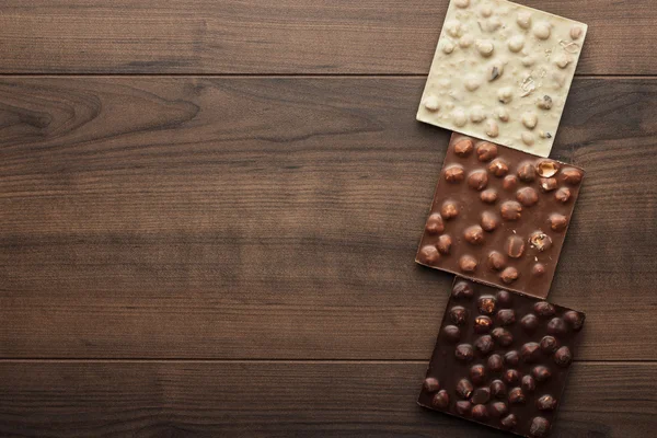 Different chocolate bars with whole hazelnuts — Stock Photo, Image