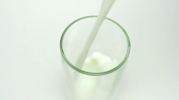 Milch füllt das Glas auf weißem Hintergrund — Stockvideo