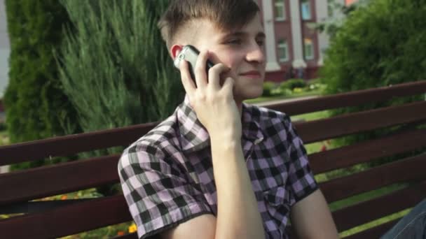 Jonge man praten over de telefoon in park — Stockvideo