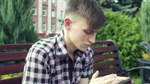 Young man with tablet computer in park steadicam shot — Stock Video