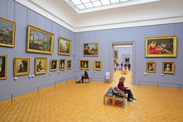 visitors look at the pictures in Louvre