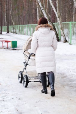 Genç annenin bebeği ile parkta yürüyor