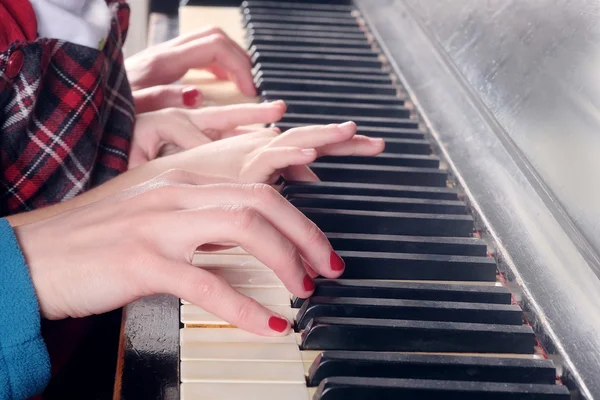 Mãos de duas pessoas tocando piano — Fotografia de Stock
