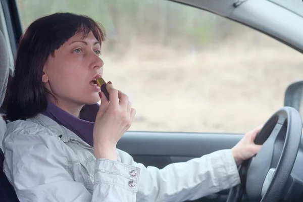 Woman make up lips at  wheel — Stock Photo, Image