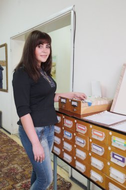 Girl-student searches something in card catalog clipart