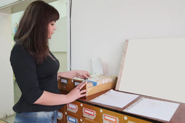 Meisje-student zoekt iets in kaartenbak — Stockfoto