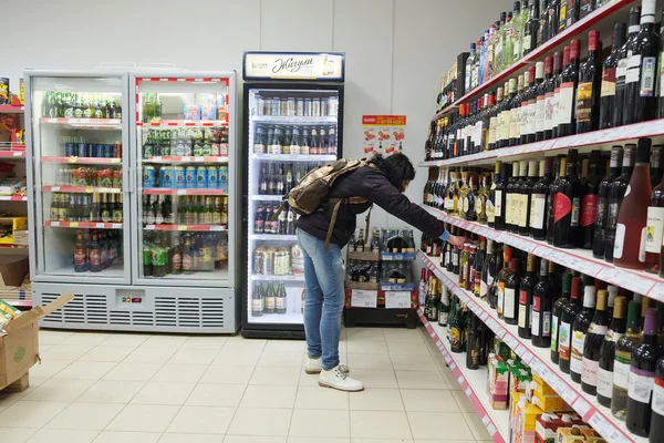 Woman is choosing a bottle of wine — Stock Photo, Image