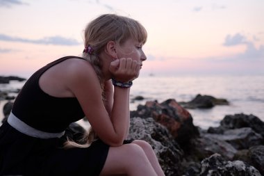 Kız bir sahil üzerinde oturur