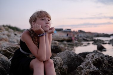 Kız bir sahil üzerinde oturur