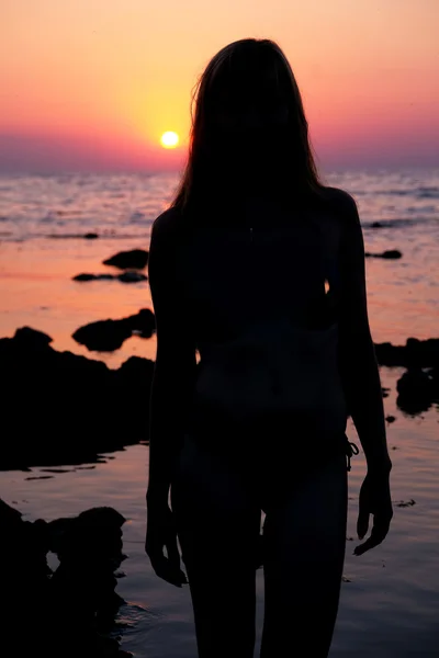 Silueta de la niña de pie junto al mar al atardecer — Foto de Stock