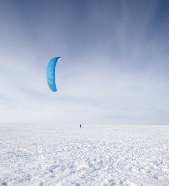 kiteboarder ile kar üzerinde mavi uçurtma