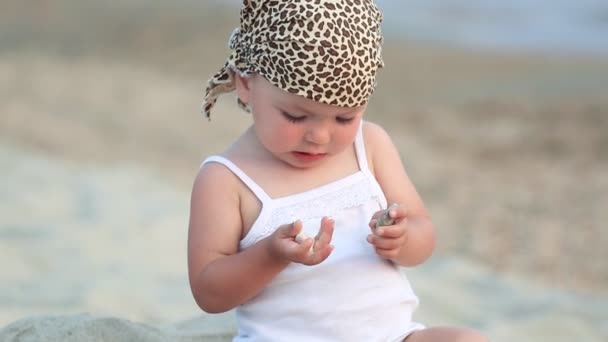 Babymeisje zitten en spelen op het strand — Stockvideo