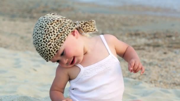 Babymeisje zitten en spelen op het strand — Stockvideo