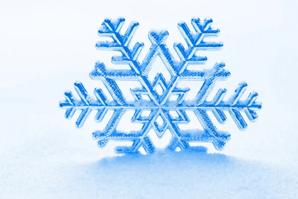 Schneeflocke vor einem Hintergrund aus Schnee — Stockfoto
