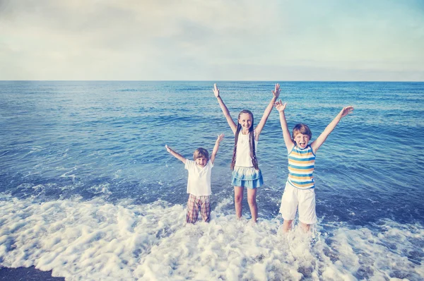 Crianças felizes correndo na praia — Fotografia de Stock