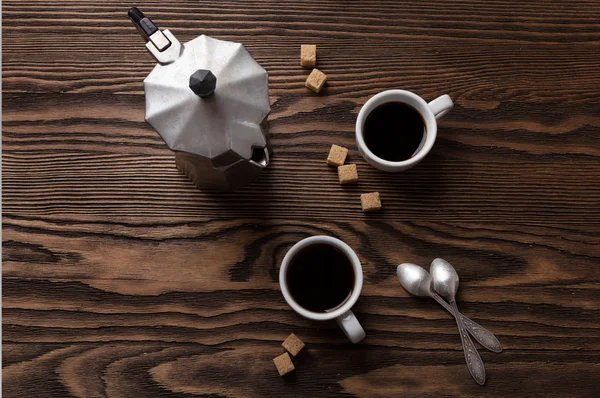 Dua cangkir espresso dengan potongan gula tebu dan pembuat kopi Italia di atas meja . — Stok Foto