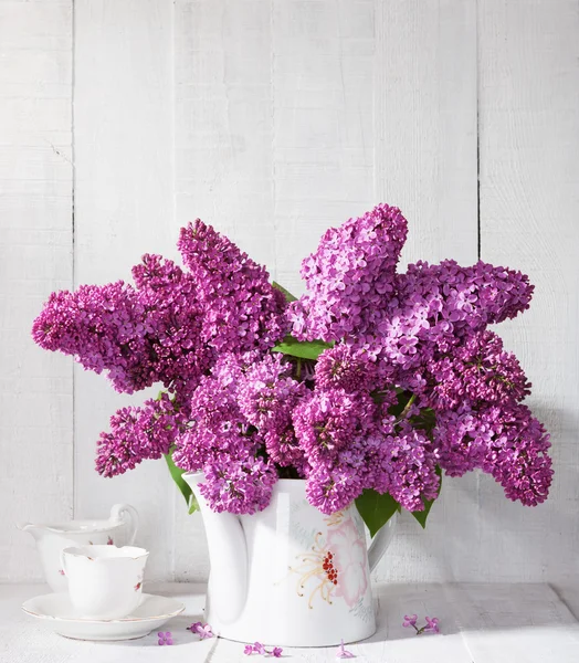 Bouquet of lilac  and cup of coffee. — Stock Photo, Image