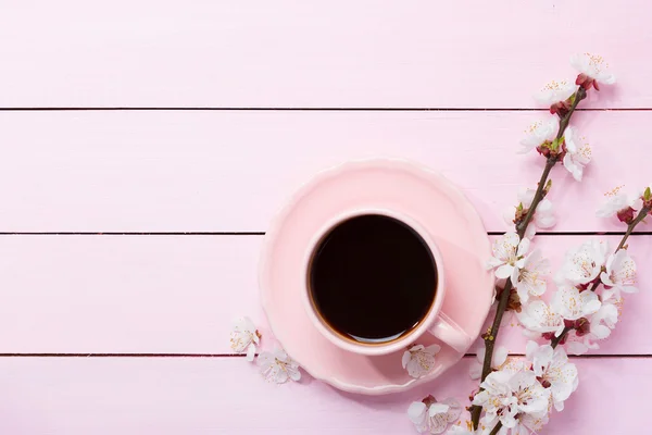 Taza de café y flores de primavera sobre mesa de madera rosa . — Foto de Stock