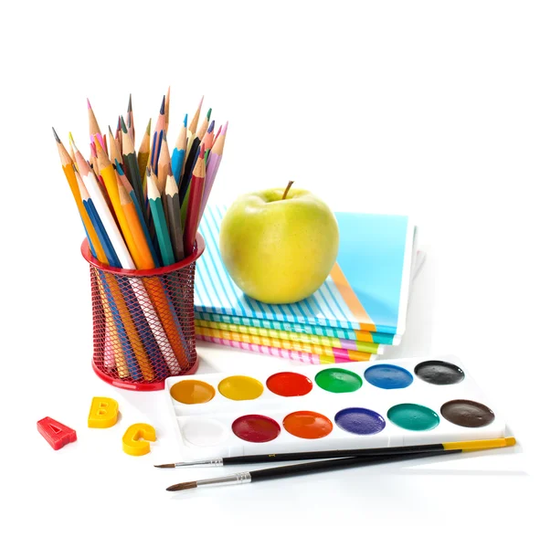 Equipamiento escolar con lápices, pinturas, pinceles y manzana . — Foto de Stock