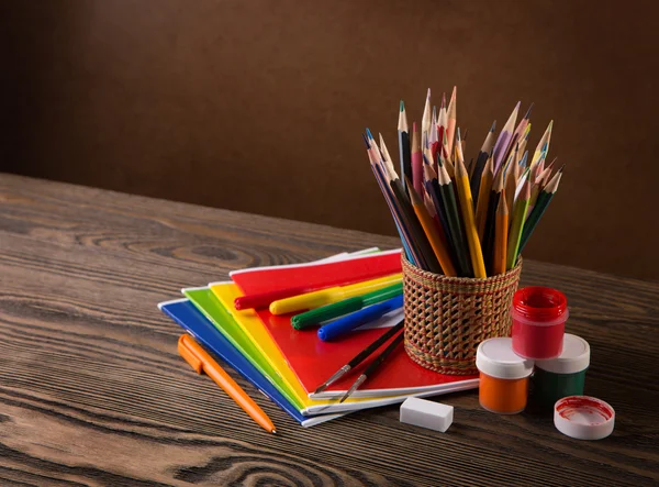 Tužky, barvy a kartáče na dřevěném stole . — Stock fotografie