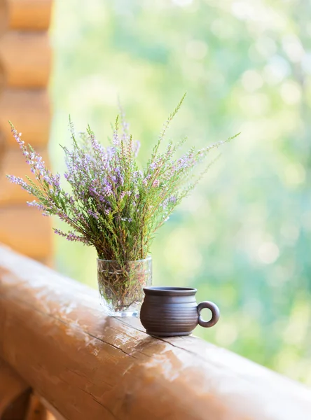 Clay šálek s kávou a kytice heathers na zábradlí balkonu. — Stock fotografie