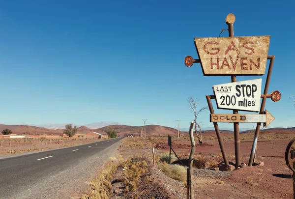 Verlassene Straße und hohes Vintage-Gasschild in typisch marokkanischer Landschaft. — Stockfoto