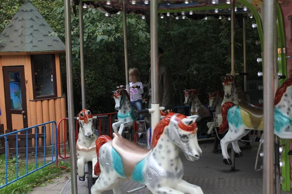 Flicka som rider på hästen på karusellen — Stockfoto