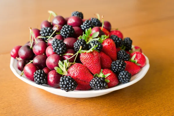 Mix of berries on wooden plate — Stock Photo, Image