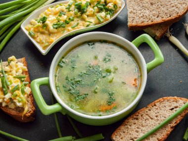 Soğuk mevsimde ısınmak ve vitamin almak için sebzeli ve yumurtalı sandviçli taze tavuk buğlonu. Sıcak ev yapımı tavuk suyu ve fırında kepekli ekmek ile kase porsiyonu..