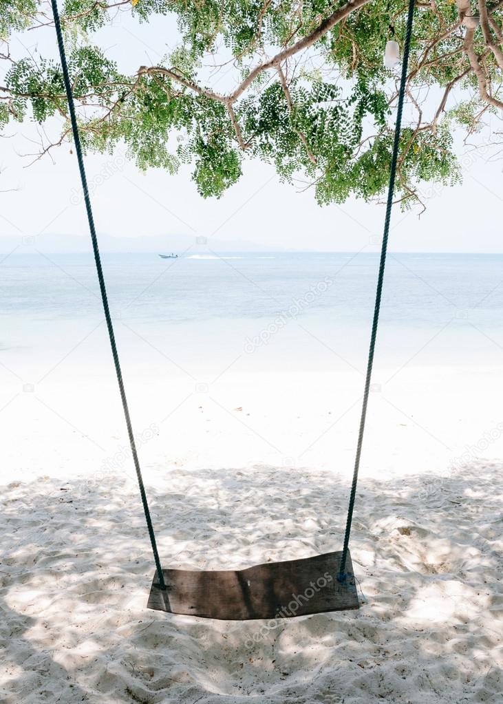 Empty swing overlooking tropical beach