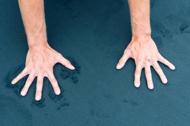 Sağ erkek el kumsaldaki kumu itiyor.