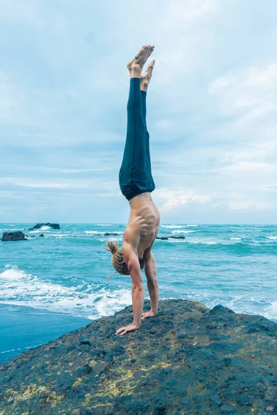 Homem atleta praticando em uma rocha com oceano — Fotografia de Stock