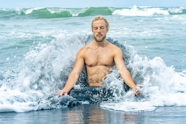 Atleet man oefenen in oceaan golven op een strand — Stockfoto