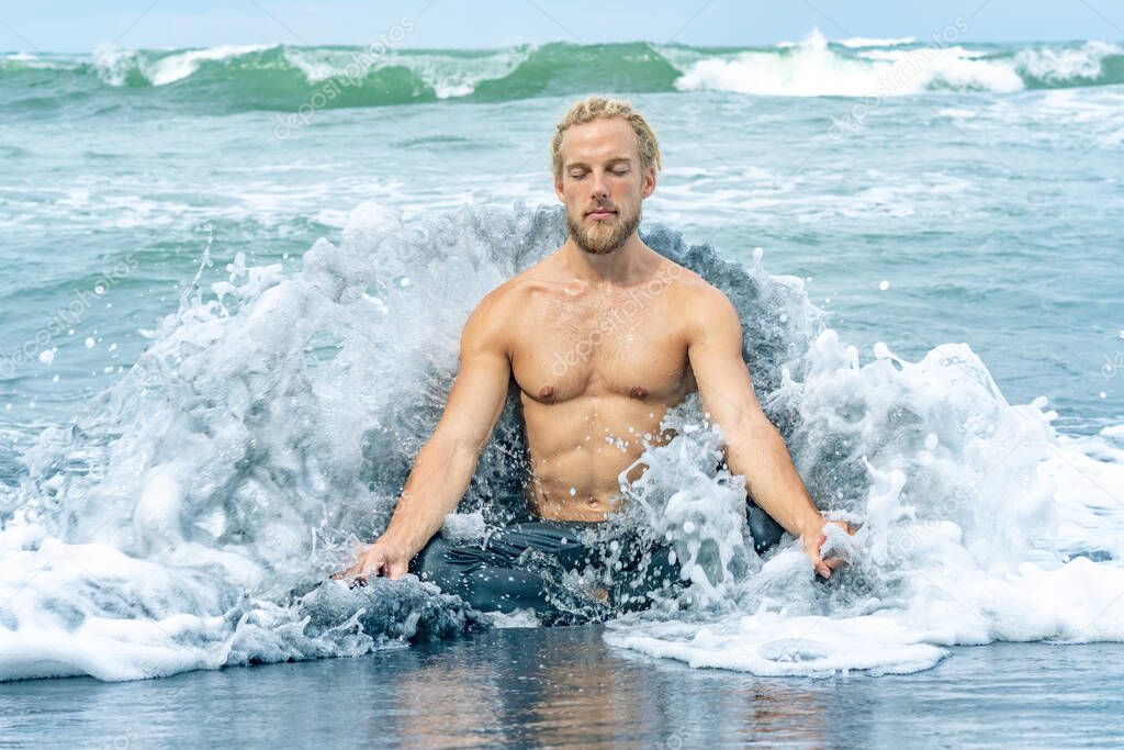 Athlete man practicing in ocean waves on a beach