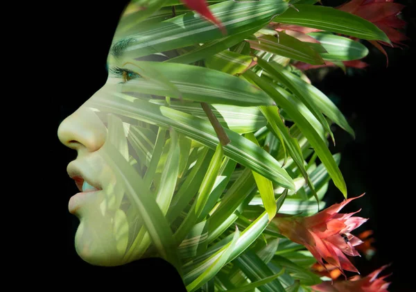 A double exposure portrait of a young womans profile against black background with tropical leaves and flowers —  Fotos de Stock