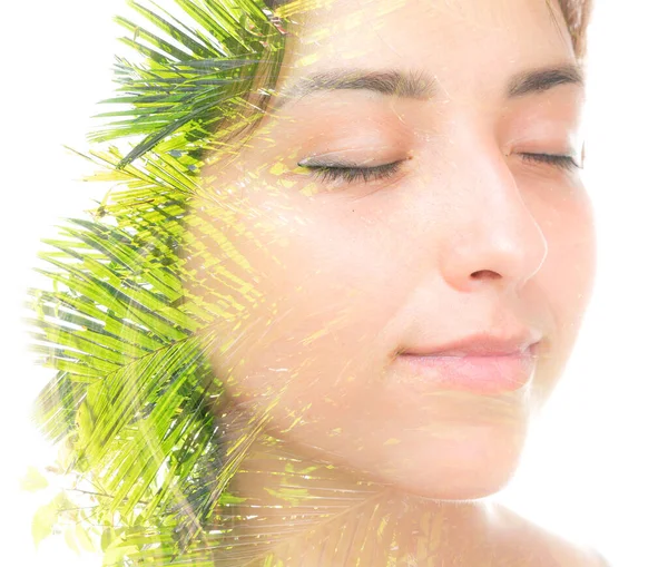 A double exposure portrait of a beautiful brunette with her eyes closed and palm tree leaves against white background — Stock Photo, Image